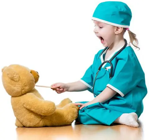 Yound child in doctor costume spoon feeding a teddy bear